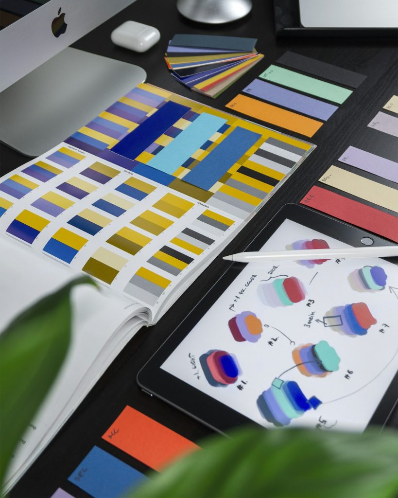 Paleta de colores y bocetos de identidad de marca sobre una mesa de diseño